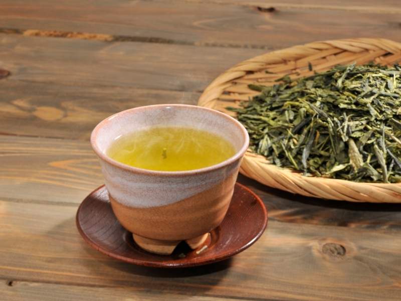 Foglie di tè verde e tazza contenente tè